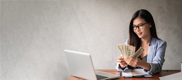 Dollar in a businesswoman's hand. An Asia woman is working from home or office and glad to get dollar money from work and from a supplementary career or Part-time self-employment with copy space and banner