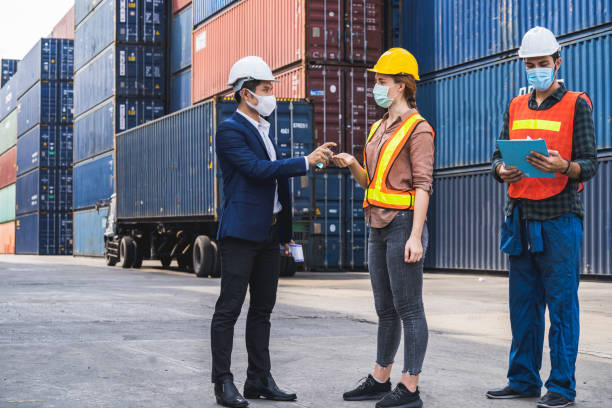 istock The supervisor wearing a protective surgical mask, standing for a physical examination and pressing the alcohol gel to colleagues before into the workplace at the warehouse container. 1277368155