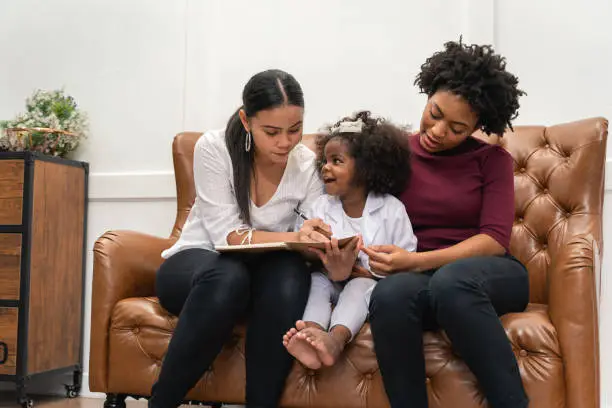 LGBT diversity Lesbian Couple Moments Happiness with her african girl laughing and drawing picture, LGBT lifestyle.