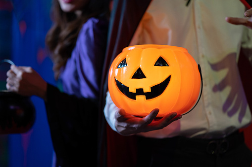Young People in Costumes Celebrating Halloween wearing Halloween Costumes at Party in Nightclub with jack-o-lantern. Celebration of Halloween
