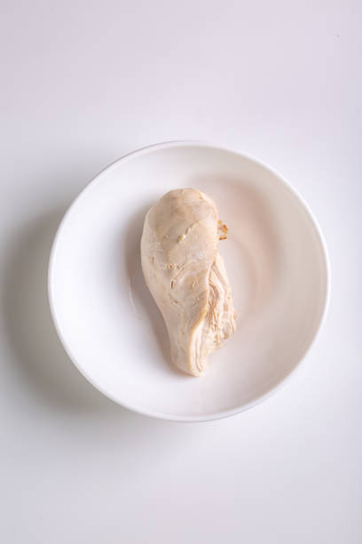 el filete de pechuga de pollo hervido está en un plato blanco sobre un fondo blanco. vista desde arriba. orientación vertical. foto de alta calidad - hervido fotografías e imágenes de stock