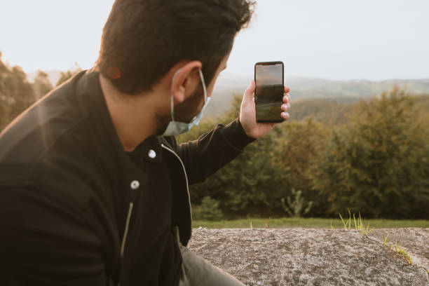 istock Young man with a protective face mask taking a photo with a smart phone 1277369470