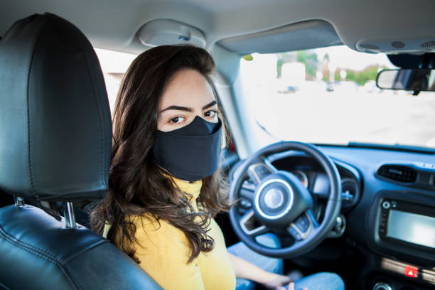 istock Young woman inside the car wearing protective face mask 1277371097