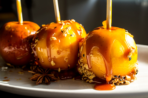 Festive caramel apples on sticks. Homemade Halloween dessert top view photo.