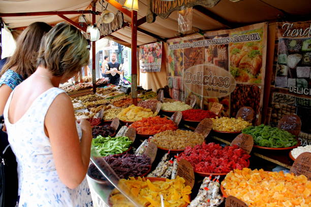 dos mujeres están viendo atentamente un puesto de caramelos y frutas secas dulces - elche españa fotografías e imágenes de stock