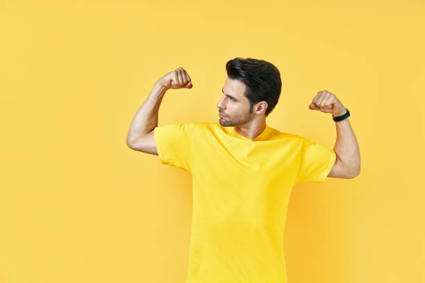 istock Handsome muscular man shows muscles on his arms on yellow background 1277377466