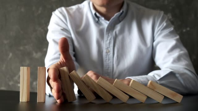 Businessman Stop Domino Effect. Risk Management and Insurance Concept