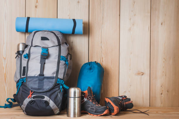istock Camping equipment, shoes, a backpack and a thermos on a wood background 1277382101