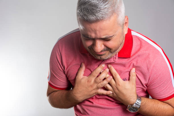 istock Mature man feeling chest pain while standing in front of grey background 1277382575