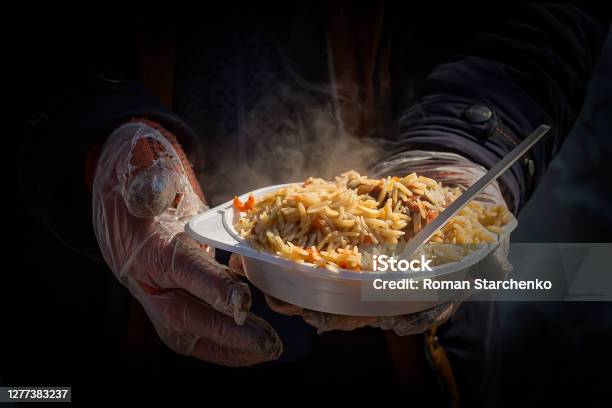 Food For The Homeless Street Food Plate With Pilaf In Hands Stock Photo - Download Image Now