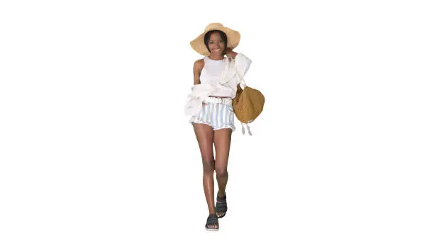 Wide shot. Front view. Summer in the city Beautiful african american woman wearing fashionable hat walking on white background. Professional shot in 4K resolution. 046. You can use it e.g. in your medical, commercial video, business, presentation, broadcast