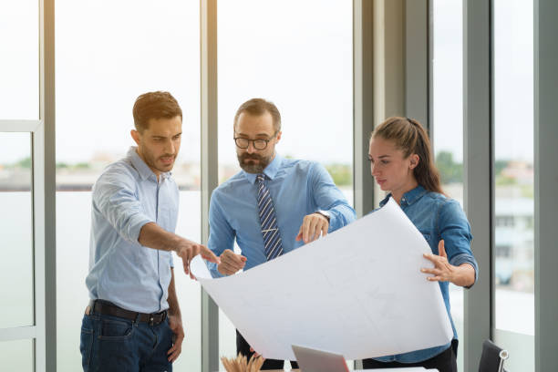 istock Team of multiethnic architects working on construction plans in meeting room. Engineers discussing on project in office. 1277383894