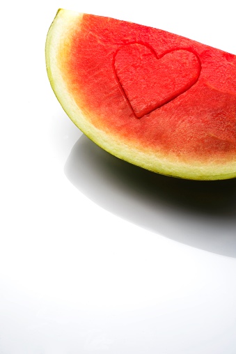 Watermelon with heart-shaped mark photographed on white background in studio.