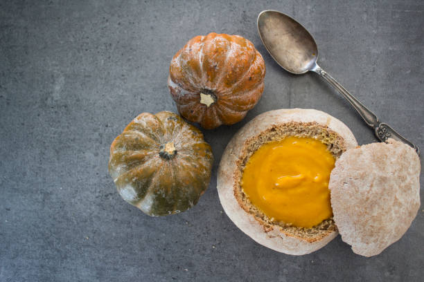 istock Pumpkin soup in fresh baked bread. Dark grey background with copy space. 1277384618