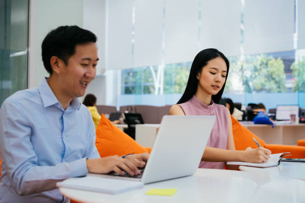 istock Cheerful business coworkers in office with notebook 1277386245