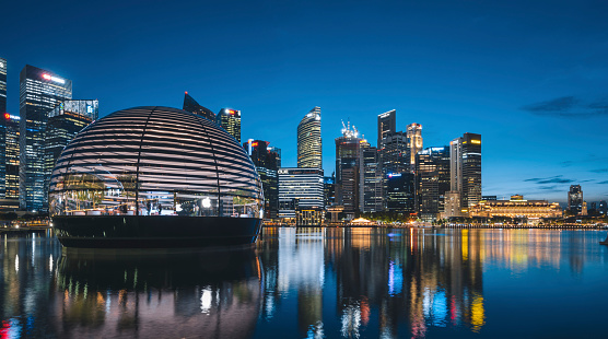 Singapore, September 10, 2020: Apple opened the worlds first floating Apple Store at the Marina Bay in Singapore at the time of this shoot. After a few days it has already become a Singapore landmark. Here the sphere shaped store seen at sunset. Behind the store the skyline of the Singapore financial district.