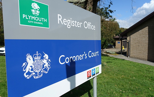 Large blue entrance sign indication the location of a Coroner's Court and Record Office for the City Of Plymouth England. Low rise brick building is the Court.