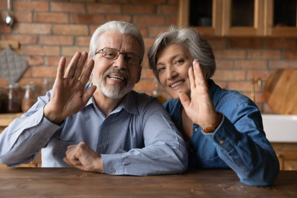 istock Smiling mature husband and wife wave talk on video call 1277387096