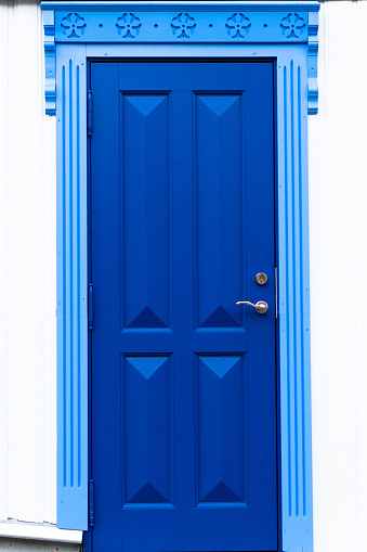 An ornate blue door in Tønsberg, Norway with two shades of blue and a carved frame