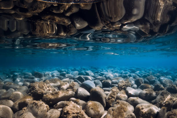 istock Underwater view with stones, reflection and blue sea water. 1277389768