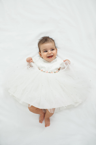 Baby girl in cute dress, lying down and smiling.