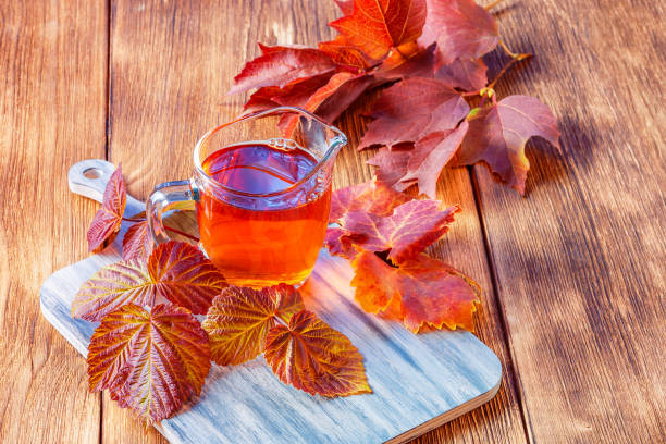 herbstkonzept trinken warmen morgentee, gesunde natürliche infusion von himbeerblättern für diekräutertherapie auf holzhintergrund - raspberry table wood autumn stock-fotos und bilder