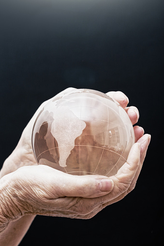 Senior woman holding a glass world globe.