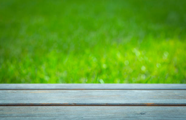 istock Background with green grass and wooden table. Empty summer sunny background 1277396905