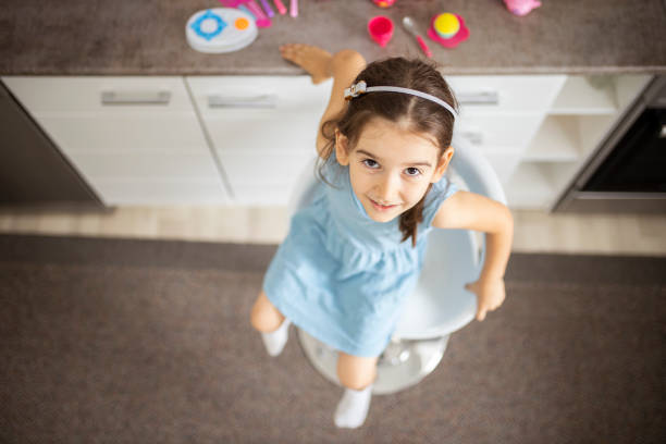 istock Beautiful girl looking up at camera while playing in the kitchen 1277397769