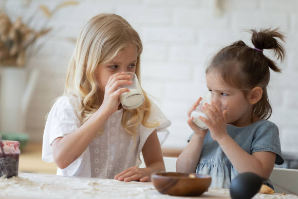 girls drinking milk from glasses - breakfast family child healthy eating imagens e fotografias de stock
