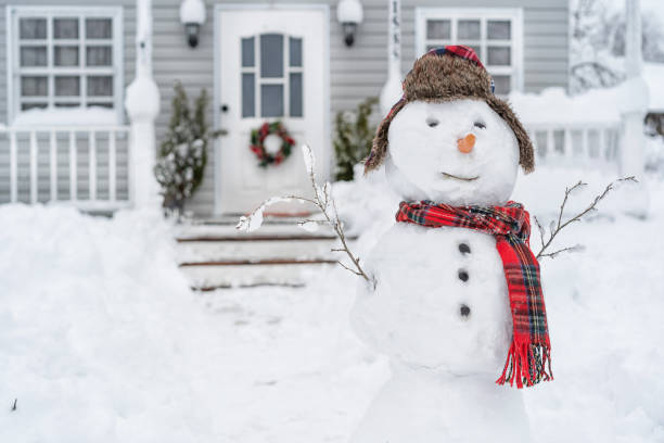 lächelnder schneemann vor dem haus am wintertag - dezember stock-fotos und bilder