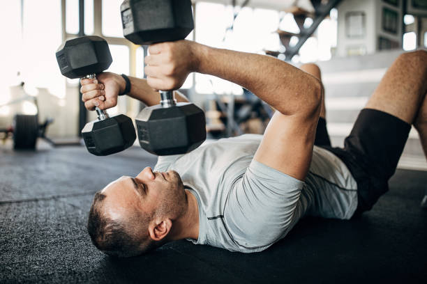 istock Strong man training with dumbbells on the floor in gym 1277402248