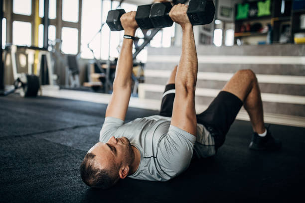 istock Strong man training with dumbbells on the floor in gym 1277403474