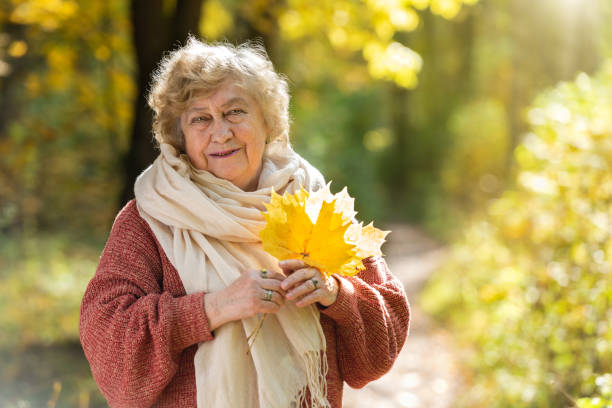 Gray-haired, smiling elderly woman in an autumn park. Happy old age, walking in nature, positive emotions. forest bathing photos stock pictures, royalty-free photos & images