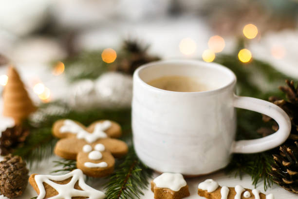 istock Coffee, homemade gingerbread cookies, pine cones decorations and warm lights on white  table 1277407006