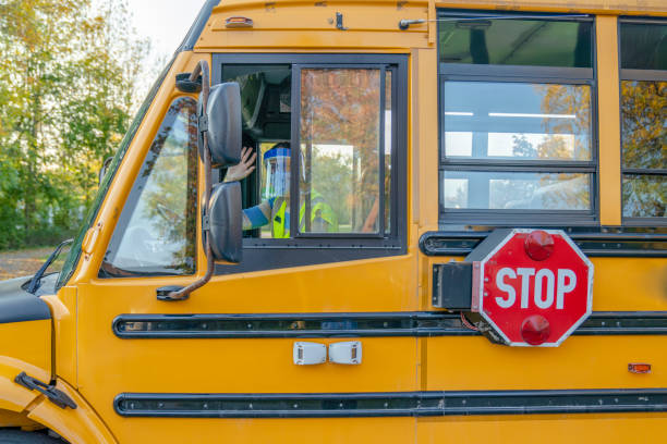 Stationary yellow school bus, focus on the stop sign on the side of the bus.