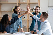 Overjoyed diverse employees giving high five at corporate meeting