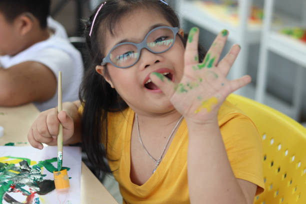 istock Disabled kids classroom, children having fun during study at school, kids learning together, schoolgirl painting in art classroom and showing her hand that stained color 1277410394