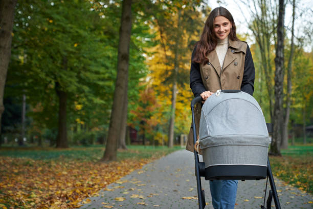 istock Woman looking at the camera and holding a stroller with newborn. 1277411524