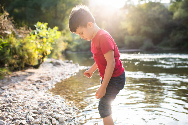 istock A cute boy standing in the river looking for rocks 1277411711