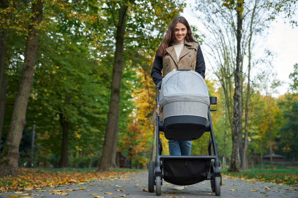 istock Woman in coat walking with a stroller in the park. 1277413302