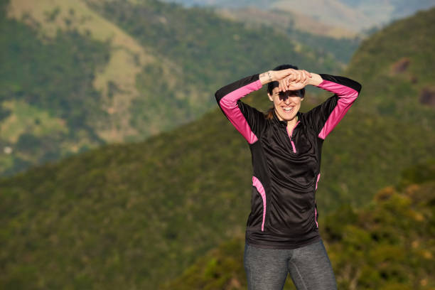Portrait of a happy woman standing on mountain top looking at camera and smiling