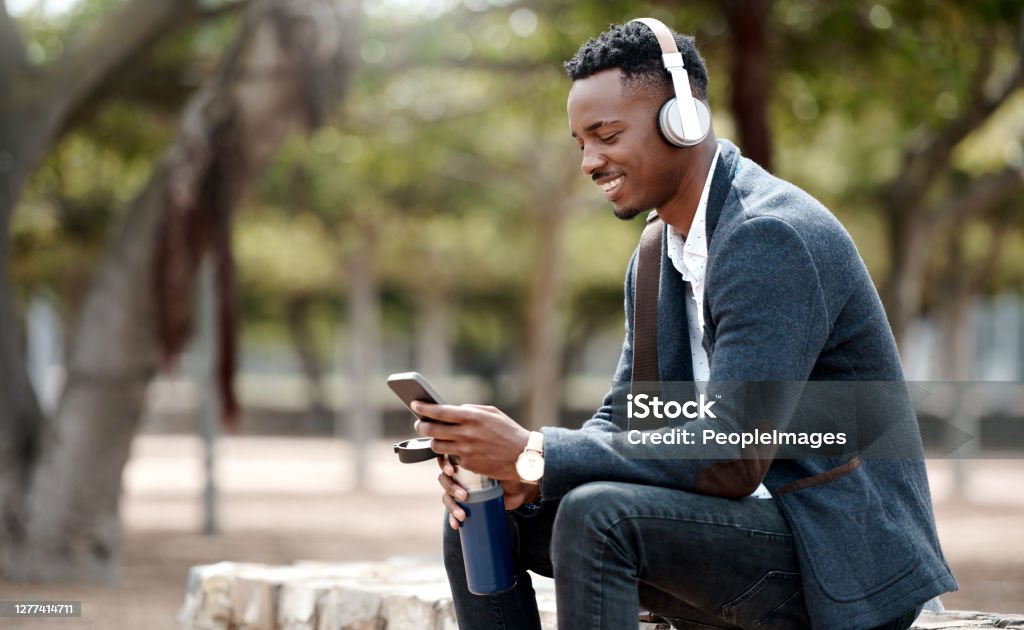 Making business as easy as a day in the park Shot of a young businessman using a smartphone and headphones in the city Listening Stock Photo