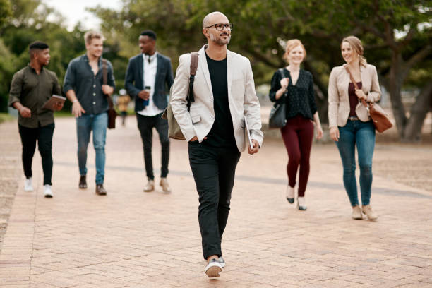 What sets you apart sets you ahead Shot of a confident mature businessman walking through the city with a young team behind him following moving activity photos stock pictures, royalty-free photos & images