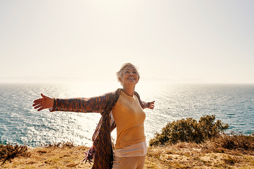 Shot of a senior woman with her arms outstretched at the beach