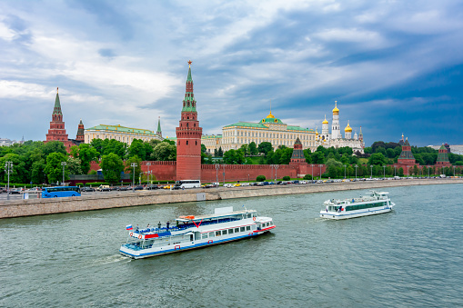 Moscow cityscape with Kremlin towers, palaces and cathedrals and boats on Moskva river, Russia