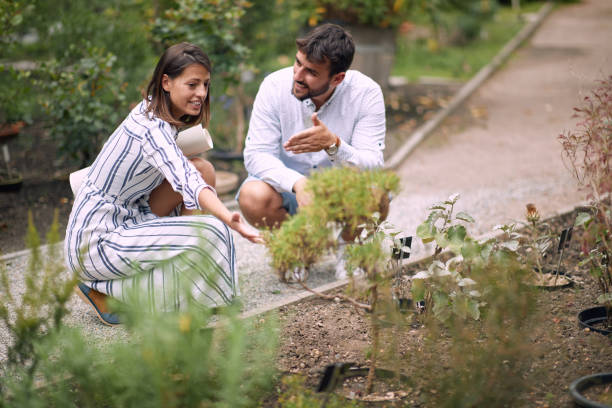 junge weibliche führerin, die einem besucher informationen über pflanzen gibt - plant formal garden nature botany stock-fotos und bilder