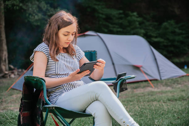 istock Young woman reading an e-book in outdoor camp 1277425624