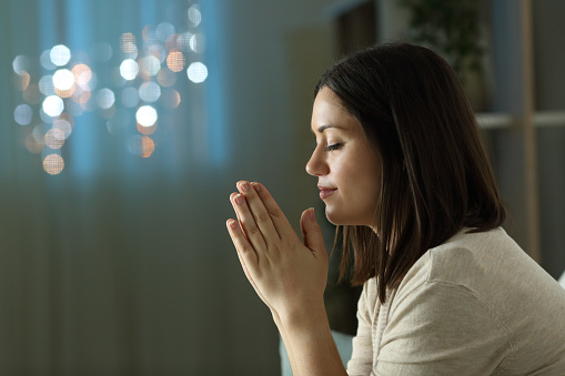 In the comfort of her home, a woman bravely facing cancer closes her eyes in meditation and prayer, seeking solace and peace amidst her battle.