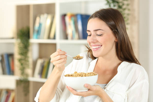 glückliche frau isst müsli zum frühstück zu hause - beautiful smiling vegetable calcium stock-fotos und bilder